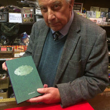 Load image into Gallery viewer, Roy Walton behind the counter in Tam Shepherds Trick Shop, holding a copy of his book &#39;The Complete Walton: Volume 3&#39;. 

